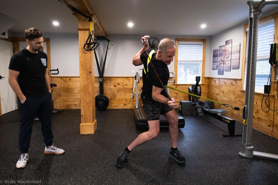 An active adult loading a resisted movement while a clinician coaches form